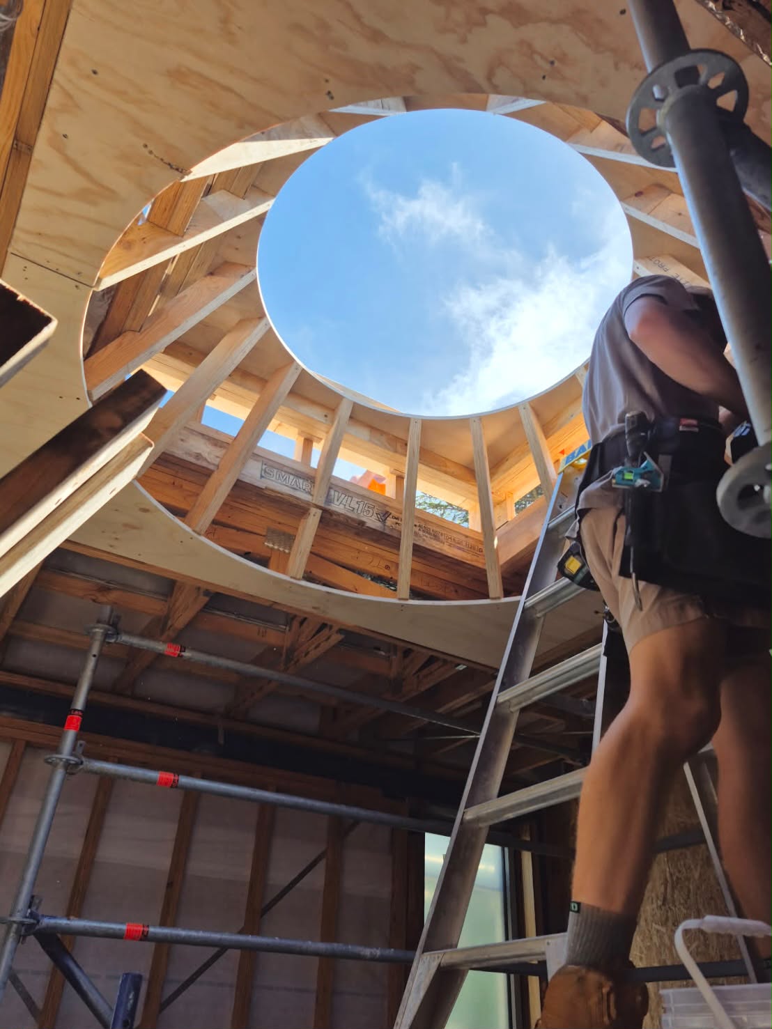 A framed oculus skylight opening to the sky during construction of an ALCHAMY residence